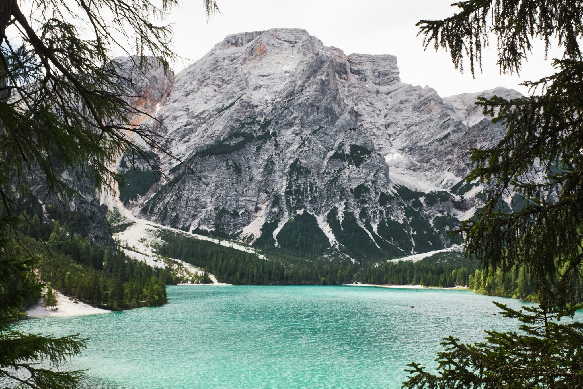 Lago di Braies: turquoise lake and rocky mountains framed by fir trees